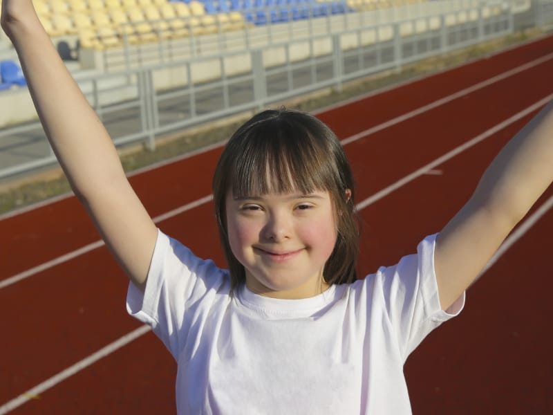 Young girl with celebration hands in the air on a track